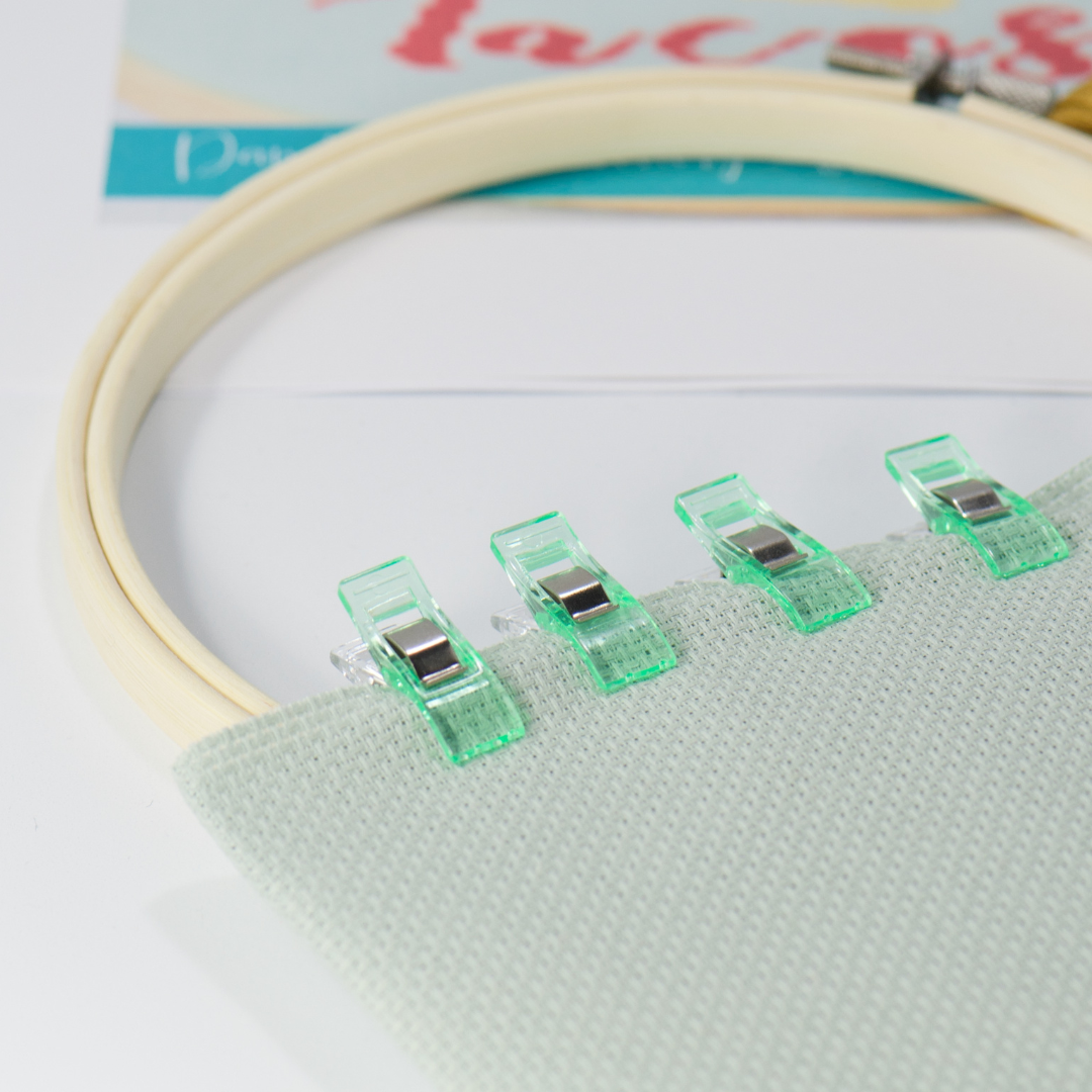 green mini clear clips holding green fabric with embroidery hoop