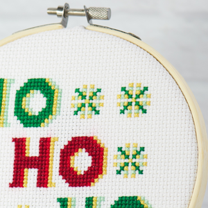 close up of red Ho cross stitch letters and green and yellow snowflakes