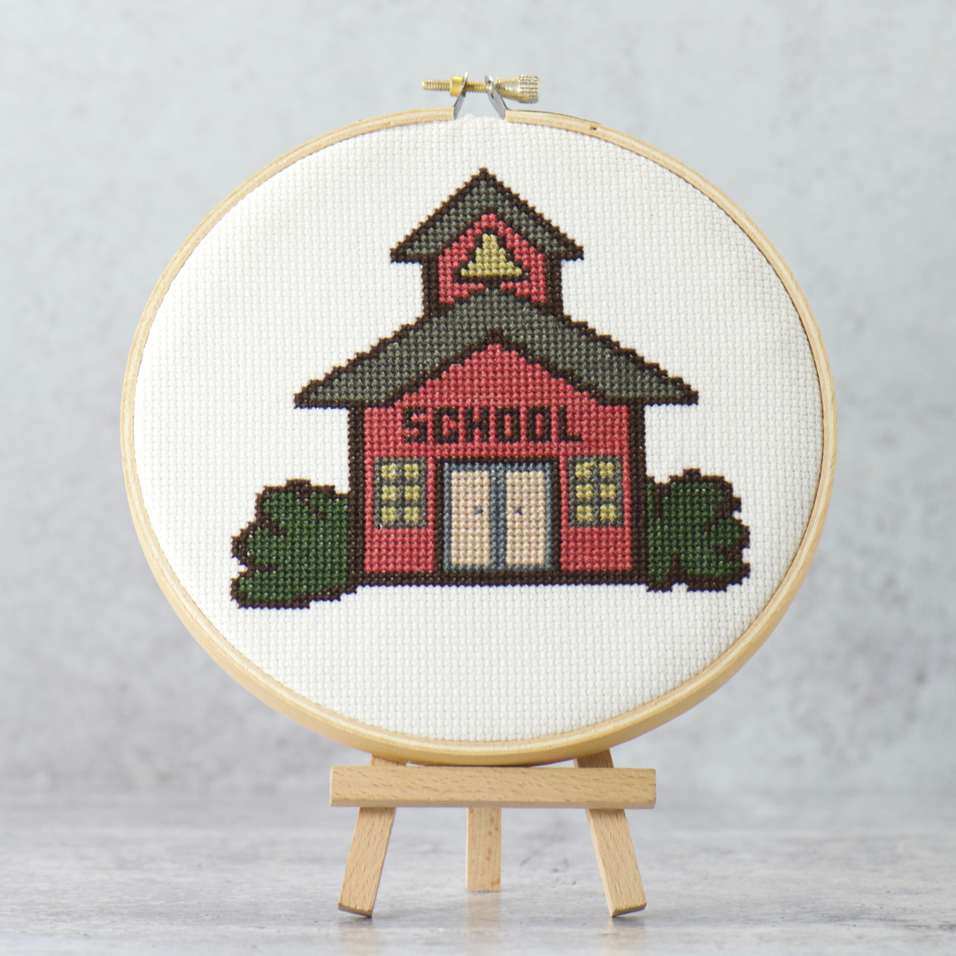 little red schoolhouse with yellow bell in tower surrounded by green bush modern cross stitch instant download digital pattern
