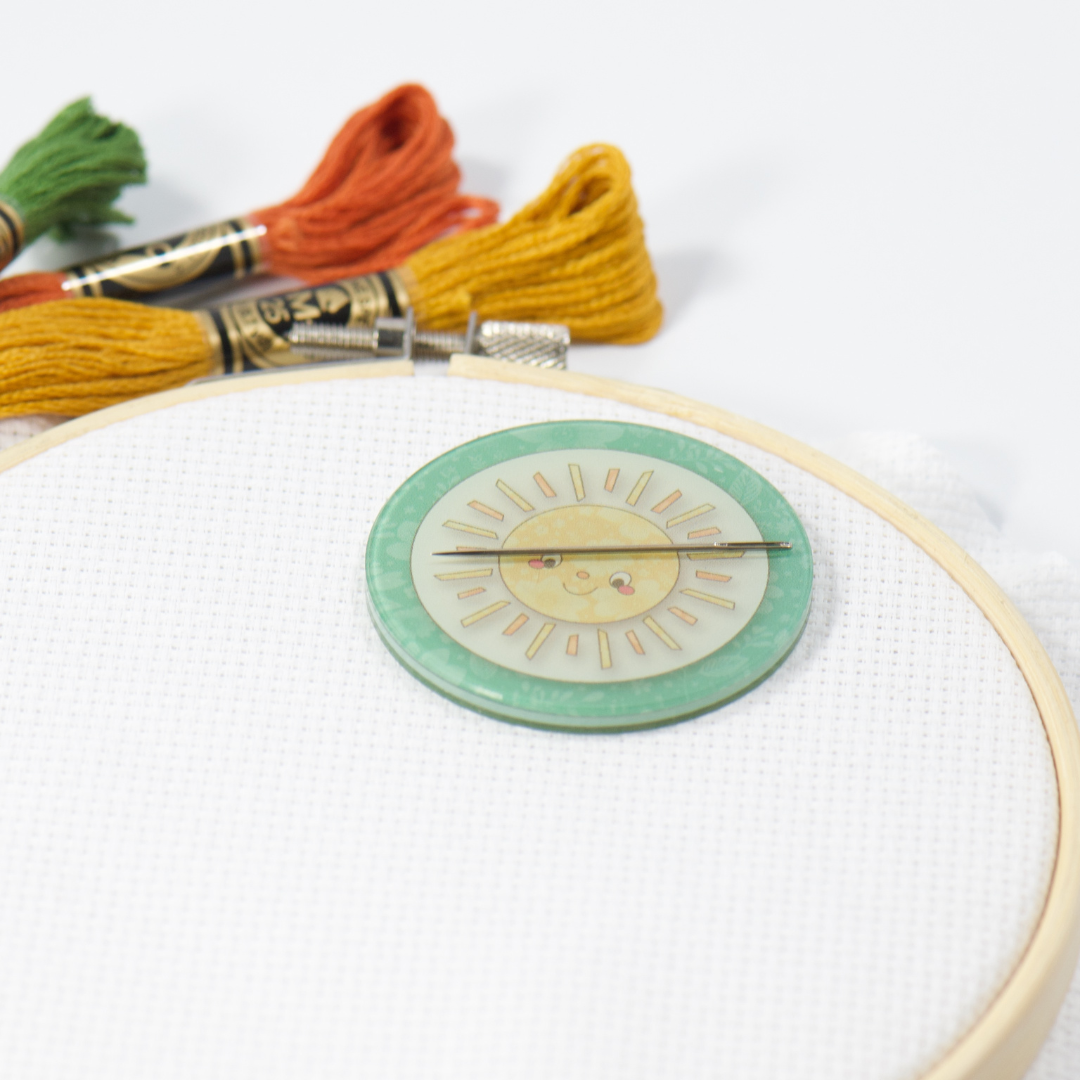 Embroidery hoop with a sun design on a white background